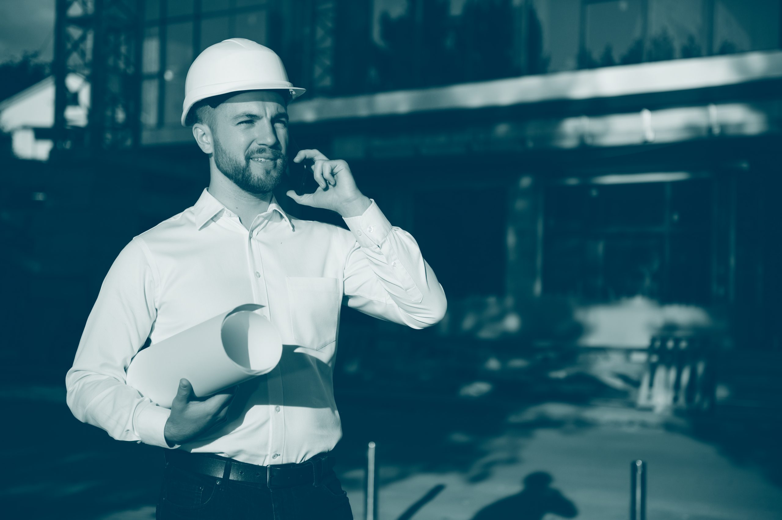 young handsome man constructor in white hardhat while on a phonecall