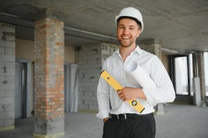 young handsome man constructor in white hardhat while on a phonecall