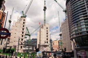 A construction project in London, England with cranes creating high rise buildings under a cloudy sky.